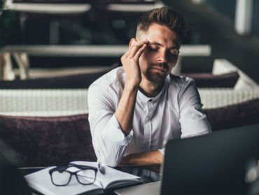 Businessman feeling headache while doing distance work in coffee shop tired with failure of plans, male entrepreneur overworked solving problems with startup project exhausted with hard schedule